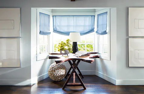 Relaxed Roman Shades made of Holland and Sherry Andes wool in Azure are used in place of bay window blinds in a coastal nook