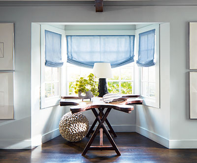Roman shades for windows include Relaxed Roman Shades made of Andes in Fountain in a bay window with a rustic driftwood table
