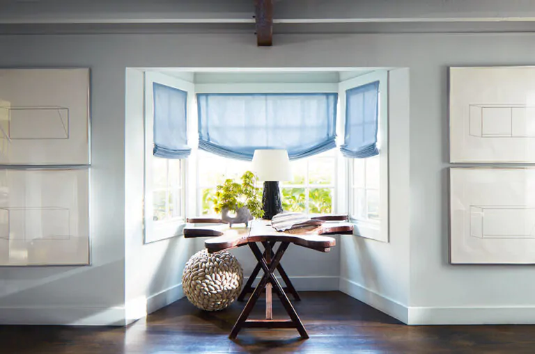 Window treatments for bay windows include Relaxed Roman Shades made of Andes in Fountain in a coastal-style nook