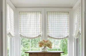 Roman shades for windows include Relaxed Roman Shades made of Emerson in Shea in a small alcove with a wooden table