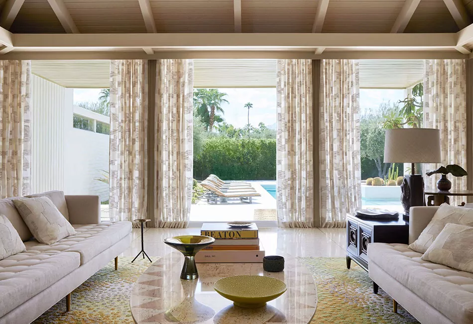 Living room curtain ideas for a modern boho transitional space includes drapes on doors that lead to a pool
