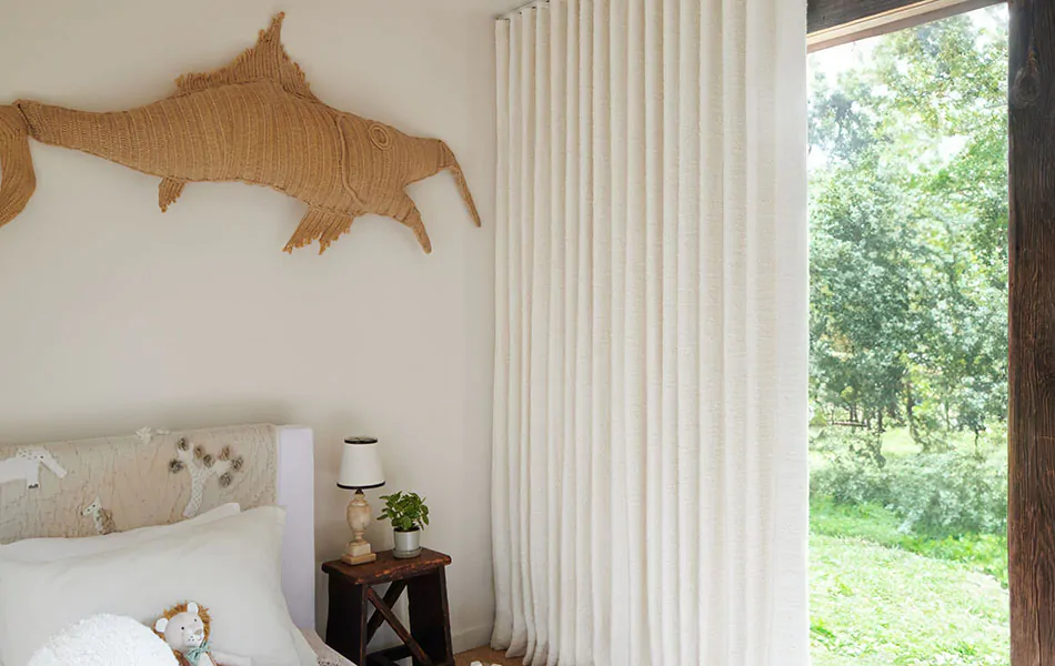 Scandinavian curtains made of Claude Stripe in Alabaster add inviting texture to a warm white bedroom with wood accents
