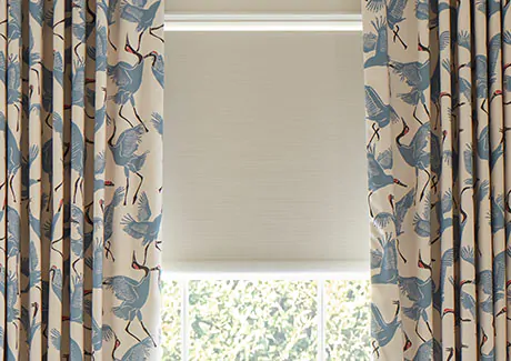 A blackout roller shade made of Ava in Birchwood adds texture beneath kids curtains made of Family of Cranes in Waverly Blue