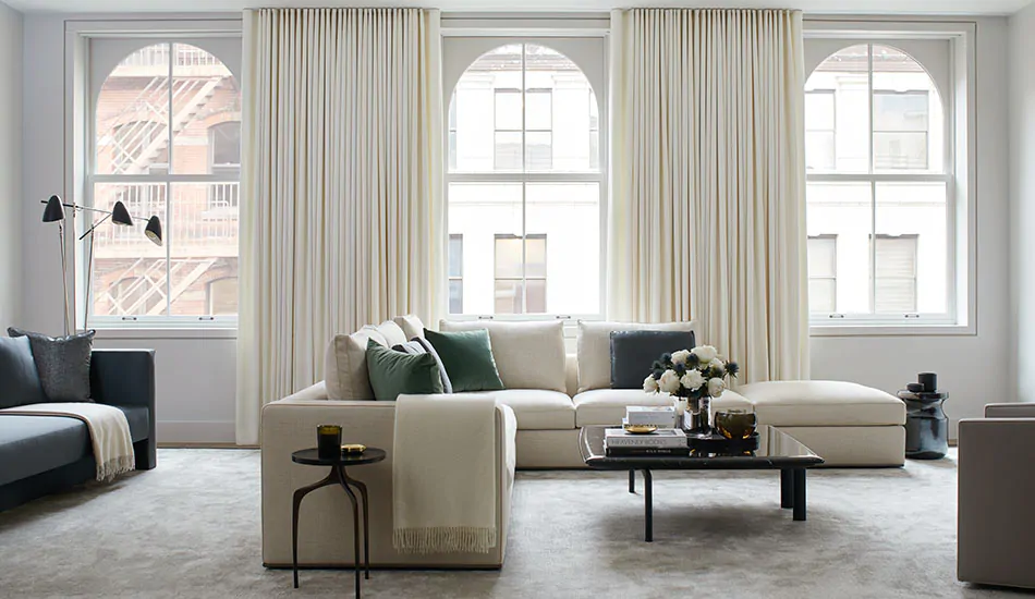 A bright living room features Ripple Fold Drapery made of Wool Flannel in Glacier which brings warmth to the room