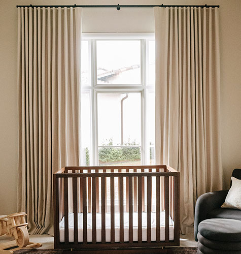 Nursery curtains made of Ripple Fold Drapery in Luxe Linen, Beige, complement the wood crib with a warn, soft, neutral look