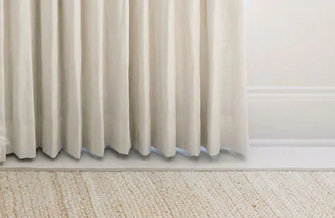 Ripple Fold Drapery made of Luxe Linen in Optic White hovers above the floor showing how to hang curtains at float length