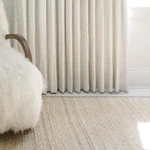 A bright room with light wood flooring and a white fur chair has white drapery floating just above the floor