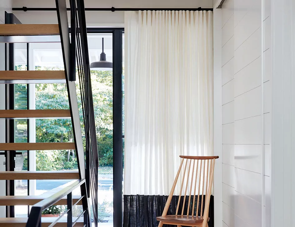Mid century modern window treatments include off-white ripple fold drapery with a black bottom border for contrast
