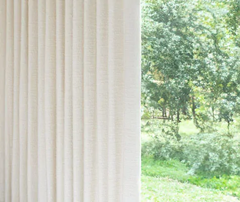 A close up of Ripple Fold Drapery made of Claude Stripe in Alabaster with blackout lining for a room darkening effect