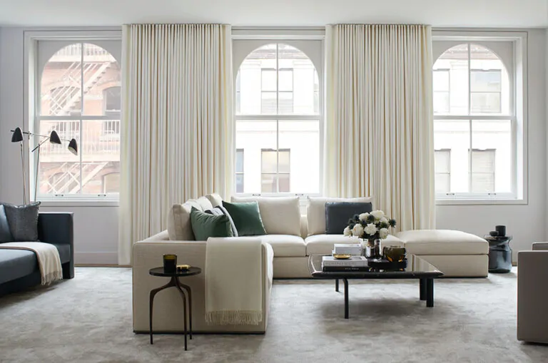 An inviting living room features floor-to-ceiling off-white curtains showing how to hang curtains in the best way