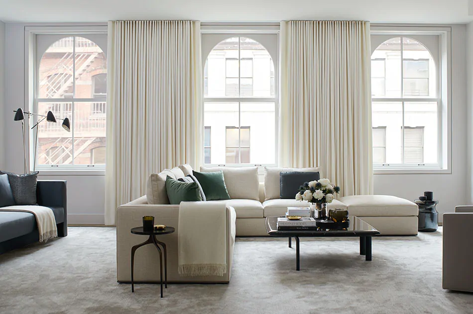 White thermal curtains pulled aside to reveal modern windows in a contemporary living room with two couches and tables