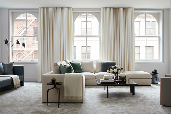 Ripple Fold Drapery made of Wool Flannel in Glacier adds a warm white tone to a bright modern living room with arched windows