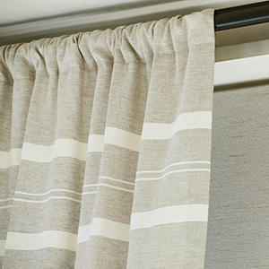 A close up of Rod Pocket Drapery made of Shoreham Stripe in Oatmeal shows gathered bunches of fabric on a curtain rod
