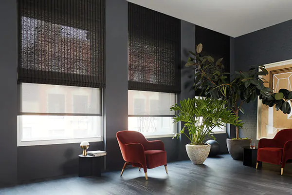 A modern room with dark grey pain and red accent chairs has Woven Wood Shades made of Laguna in Coffee