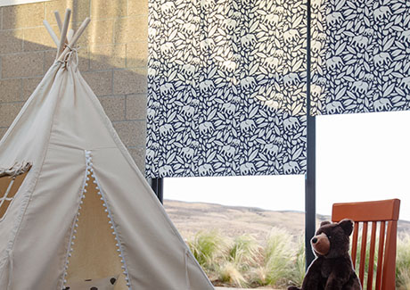 Window coverings in a kids room with a teepee and stuffed bear include Roller Shades made of Eleo in Navy