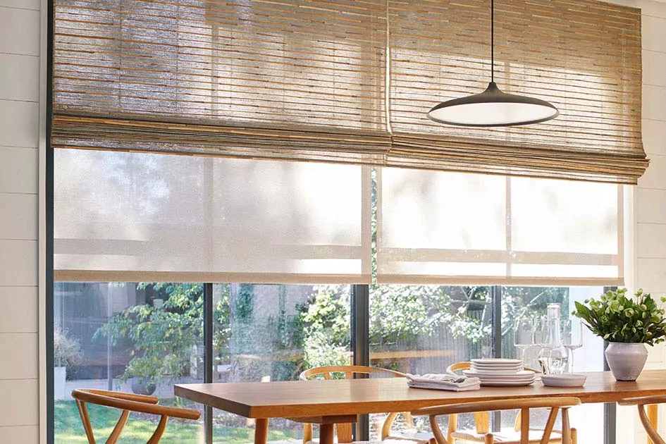 Window treatments for mid century modern homes include a tan roller shade paired with a light wood toned woven wood shade