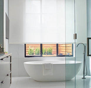A bright modern bathroom features a Roller Shade made of Sullivan material in white, ideal for a minimalist aesthetic