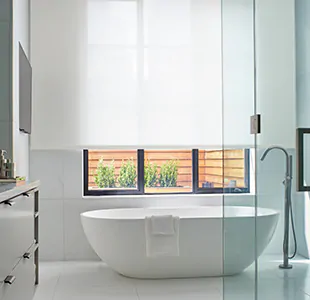 A bright modern bathroom features a Roller Shade made of Sullivan material in white, ideal for a minimalist aesthetic