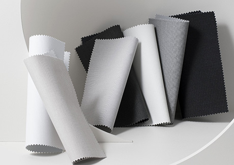 Roller Shade swatches made of Irving blackout material in neutral colors are decoratively displayed on a white background