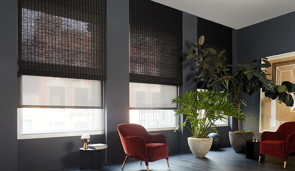 Contemporary window treatments in a dark mid-century modern living room include dark gray solar shades under black woven wood shades