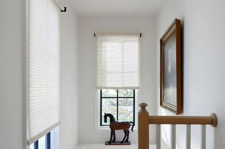 A stairwell with a horse figurine has Roller Shades made with roller shade parts including Mesa Verde material in Sand