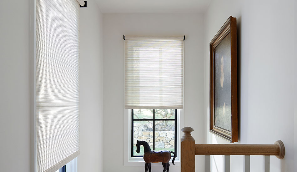 A stairwell with a horse figurine on a ledge features motorized Roller Shades made of Mesa Verde in Sand for added texture