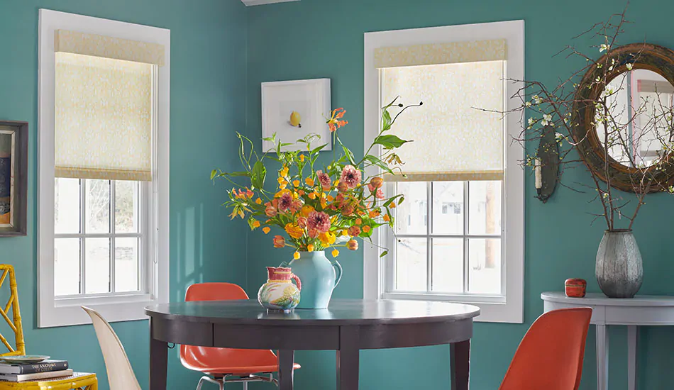 A room painted turquoise features sleek Roller Shades with a hard valance showing the difference between a cornice vs valance