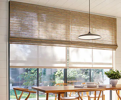 A sunny dining room has Woven Wood Shades and Roller Shades as an alternative to blinds for tall windows