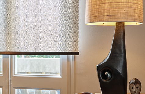 Roller Shades in a warmly decorated room feature a tea leaf pattern in brown and are used in place of blinds for a bay window