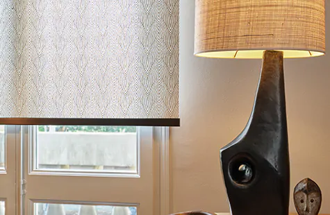 Roller Shades in a warmly decorated room feature a tea leaf pattern in brown and are used in place of bay window blinds