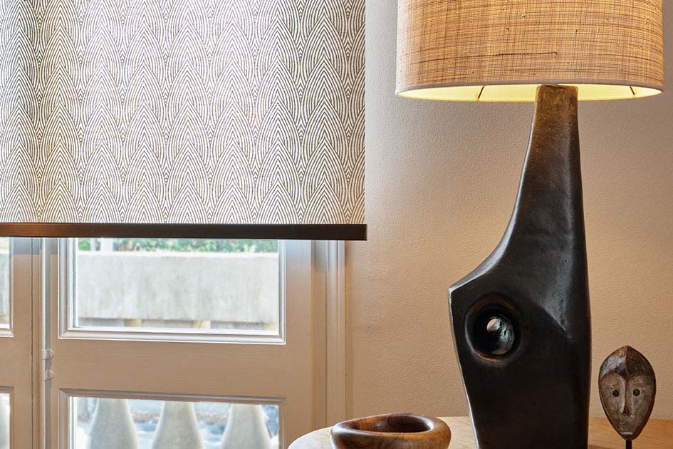 Mid century modern window treatments include a sleek roller shade with a tea leaf pattern and eclectic decor
