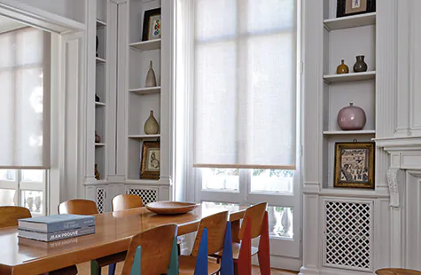 A mid-century modern dining room features French doors covered by a Roller Shade made of Techno in Linen which filters light