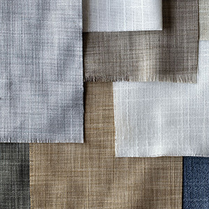 Roman Shade swatches made of Korinthos fabric are laid flat and feature frayed edges and neutral colors