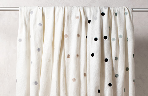 Linen Dot fabric in different colors hangs from a line and offers a playful polka dot design for linen Roman Shades