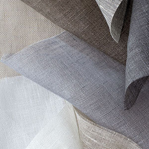 Luxe Sheer Linen fabrics swatches are piled together and offer a luxurious tactile experience for linen Roman Shades