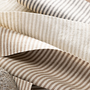 Swatches of Nate Berkus' Surrey Stripe lay invitingly on a surface and offer a versatile stripe for linen Roman Shades