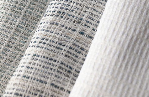 Shoreline fabric in three colors is folded and stacked and delivers a rustic, textured look for linen Roman Shades