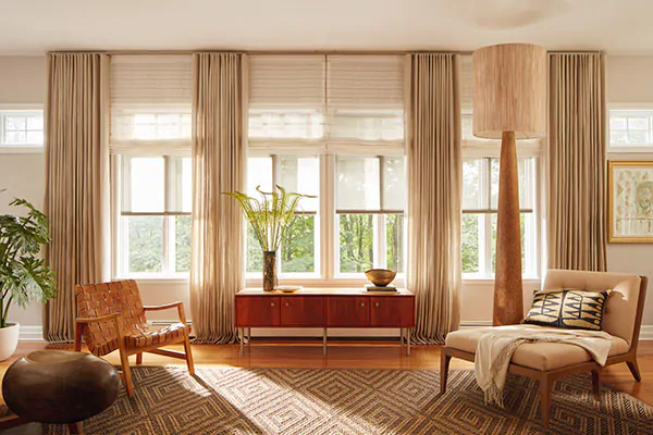 A warm inviting room has beige tones through layers of window treatments including Drapery, Roman Shades and Solar Shades