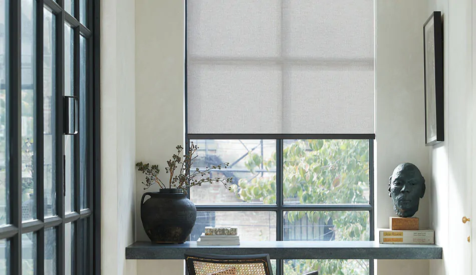 A tall narrow window in an office features a solar shade made from 5 percent Sunbrella Solistico in Slate