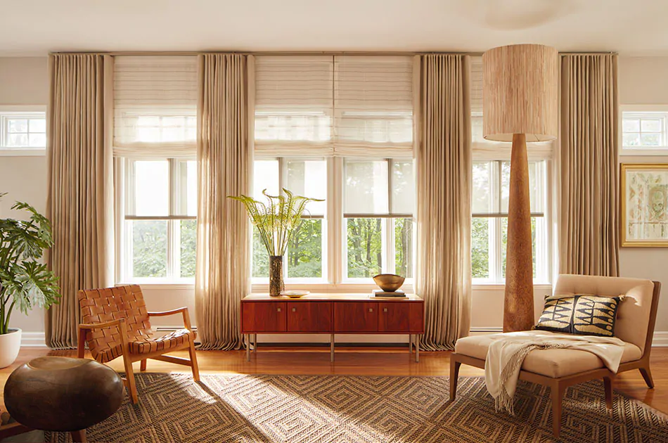Privacy shades including Flat Roman Shades and Solar Shades adorn large windows along with drapery in an inviting living room