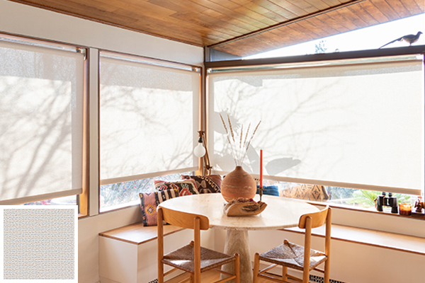 A sunny breakfast nook with a small table on an upper floor of a house with solar shades for windows pulled down
