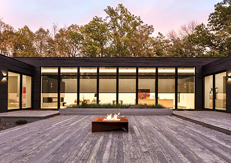 A modern home has Solar Shades at night made of 10% material in Black that you can see through during the night from the deck