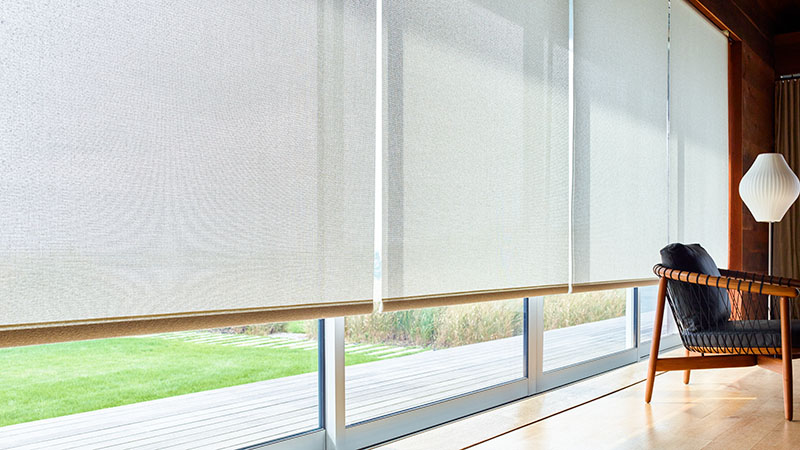Solar shades for windows drawn low along a wall of large windows reducing glare from the sun into the room