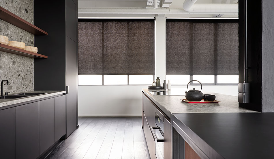 Dark solar shades for windows drawn low in a modern kitchen that is still receiving a lot of sunlight