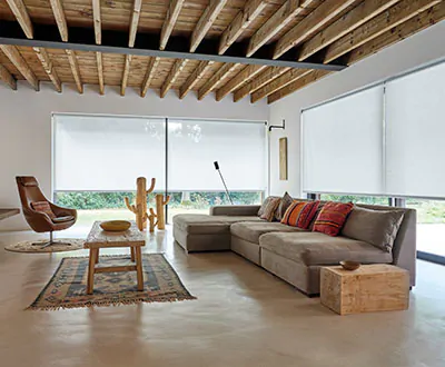 An open, minimalist living room is flanked on two sides by nearly floor-to-ceiling windows with solar shades