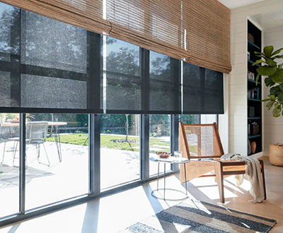 A row of solar shades for windows pulled to about mid-height with an outer layer of woven wood shades in a living room