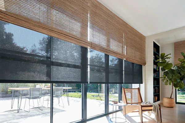 Solar Shades at night can give you more privacy when paired with Waterfall Woven Wood Shades made of Coastline in Oat