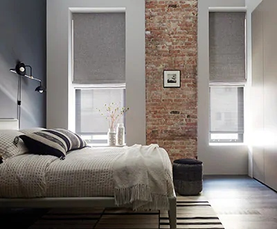 A bedroom has tall narrow windows with Flat Roman Shades and Solar Shades as an alternative to blinds for tall windows