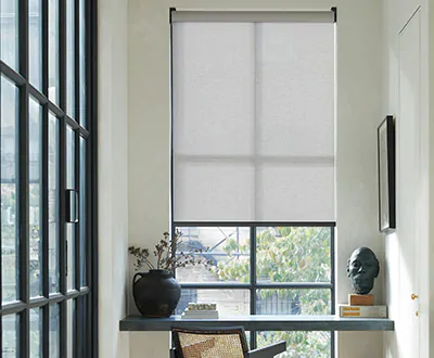An office in a bright hallway has a Solar Shade in 5% Solistico, Slate, as an alternative to blinds for tall windows