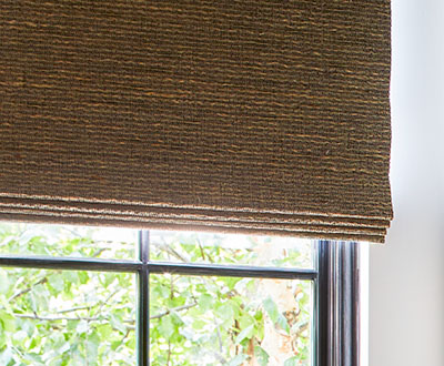 A close up of blackout lined woven shades made of Artisan Weaves Beacon in Cinder shows how the light is blocked